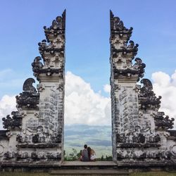 Rear view of couple sitting on entrance against sky