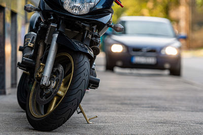 A motorcycle parked on the sidewalk with a blurred city street with cars in the background