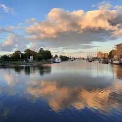 Scenic view of river by buildings against sky