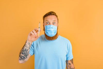 Portrait of man standing against yellow background