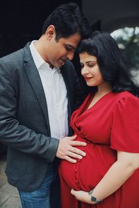 Man standing with hands on stomach of pregnant woman