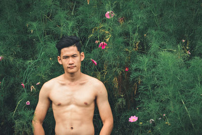 Portrait of shirtless young man standing in garden