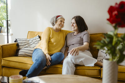 Happy senior woman talking with daughter-in-law while sitting on sofa at home