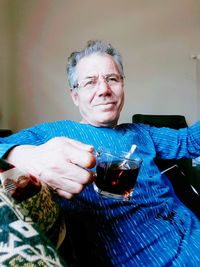 Portrait of senior man having drink while sitting at home