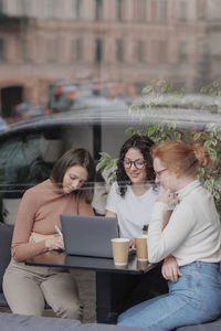 Friends using phone while sitting in city