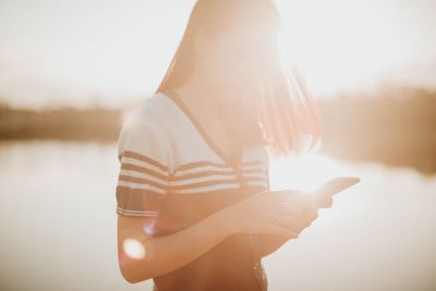 Midsection of woman holding sun against sky