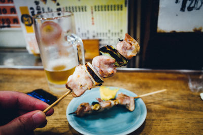 Cropped image of person holding food while sitting on table