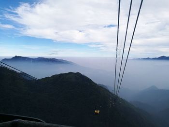 Overhead cable car over mountains against sky