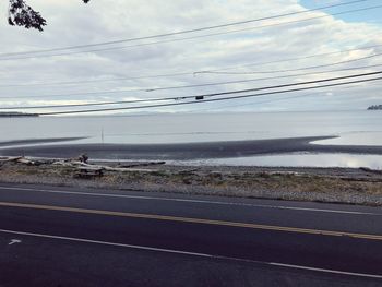 Scenic view of road by sea against sky