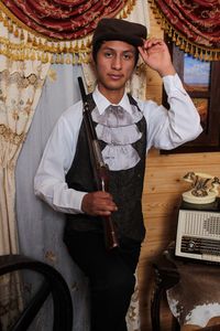 Portrait of young man in costume holding rifle at home