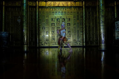 Man standing against illuminated wall with reflection