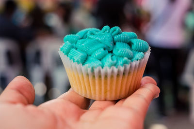 Cropped hand of person holding cupcake outdoors