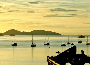 Sailboats in sea against sky during sunset