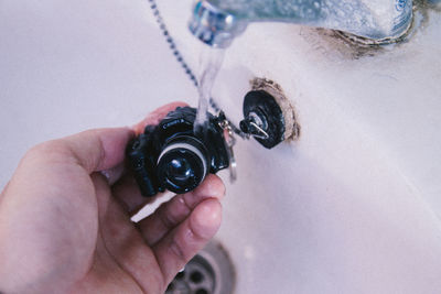 High angle view of hand holding faucet in bathroom