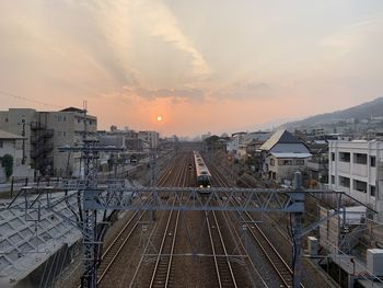 High angle view of railroad tracks amidst buildings against sky during sunset