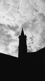 Low angle view of silhouette building against cloudy sky