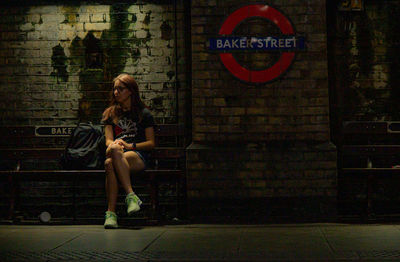 Portrait of young woman sitting on station bench