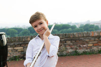 Portrait of boy holding flute against clear sky