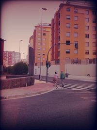 Man crossing road against buildings in city