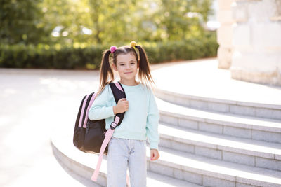 Smiling sweet happy little kid girl 5-6 year old wear casual clothes and backpack. 