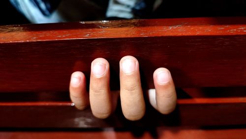 Fingers of a little boy is on the bench