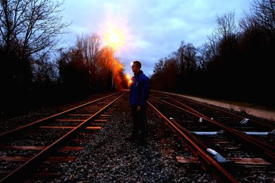 Rear view of man standing on railroad tracks against sky