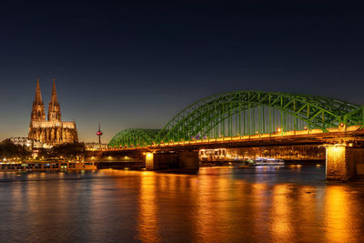 Illuminated bridge over river at night