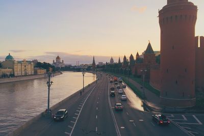 Cars on road in city against sky during sunset