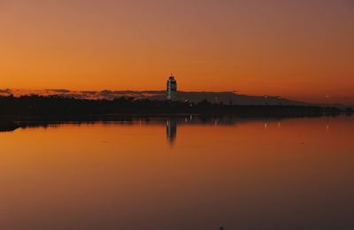 Silhouette lighthouse against orange sky during sunset