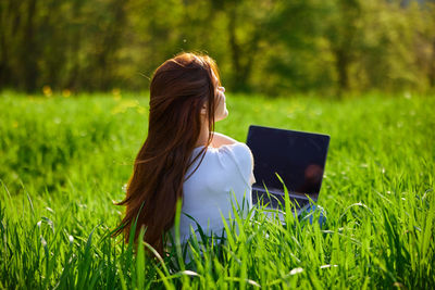 Rear view of woman sitting on grassy field