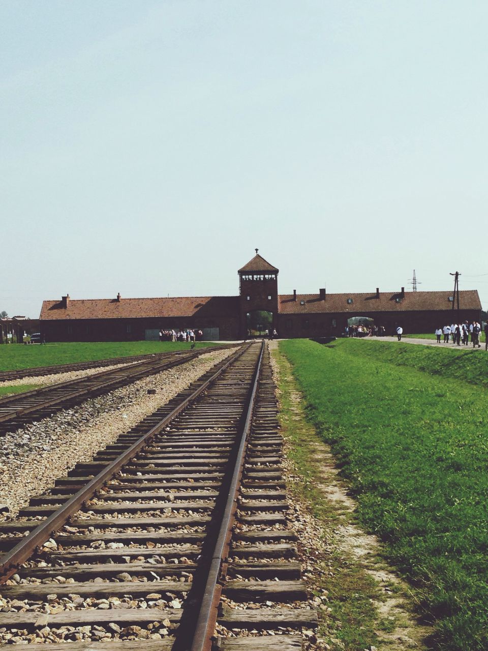 clear sky, railroad track, grass, copy space, built structure, field, architecture, the way forward, rail transportation, building exterior, day, rural scene, landscape, sky, outdoors, diminishing perspective, no people, nature, agriculture, vanishing point