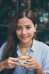 Portrait of smiling young woman having coffee at restaurant
