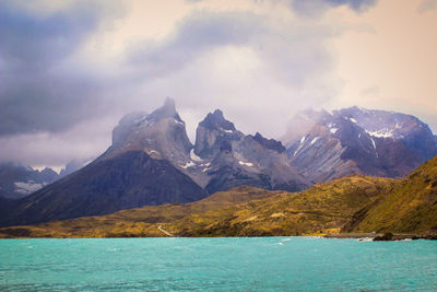 Scenic view of sea and mountains against cloudy sky