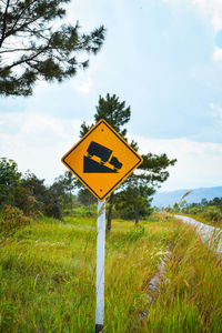 Road sign on field against sky