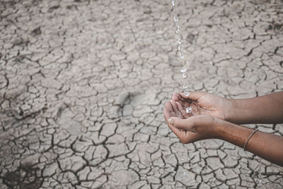 Cropped image of hand holding water against barren land