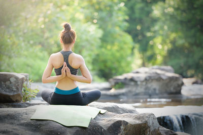 Rear view of woman sitting on rock