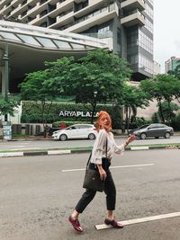 Full length portrait of woman standing on road in city