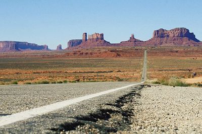 Road amidst field against monument valley