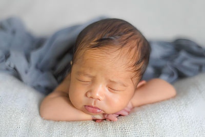 Close-up of cute baby boy lying on bed at home