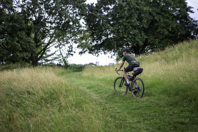 Full length of man riding bicycle on grassy land