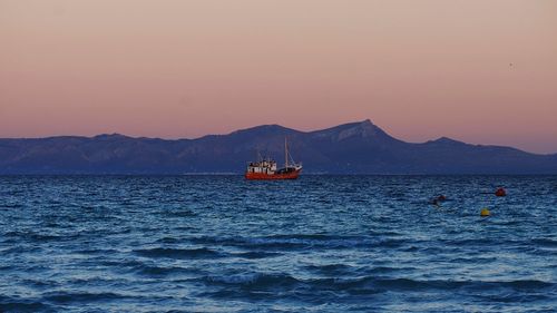 Boat sailing on sea against clear sky during sunset