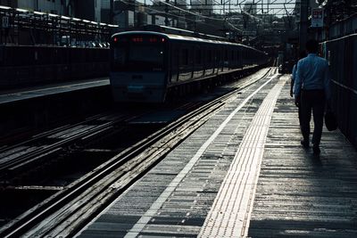 Rear view of man standing at railroad station