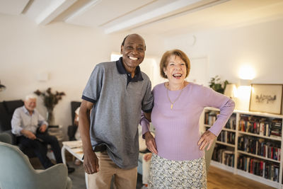 Portrait of happy senior man standing with arm around woman at nursing home