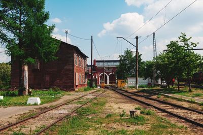 Railroad tracks by trees and buildings against sky