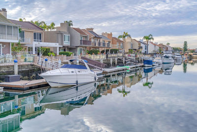 Boats moored at harbor by buildings against sky