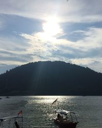 Boats in sea against cloudy sky