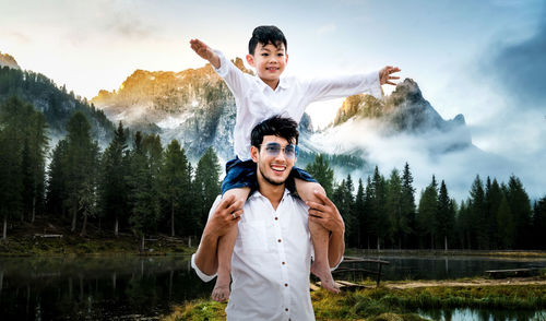 Happy young man standing by water against sky