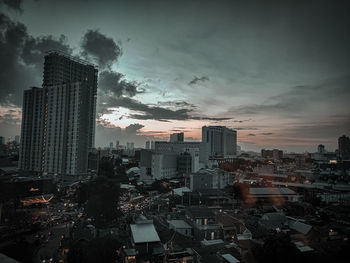 Aerial view of buildings in city at sunset