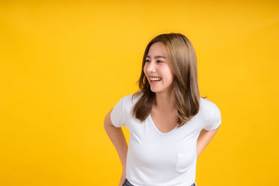 Smiling young woman against yellow background