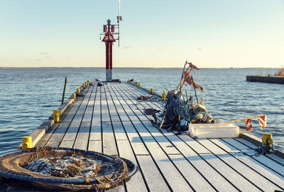 Frozen pier with fishing accessories - red flags, anchors, net, ropes and seagulls in  winter day